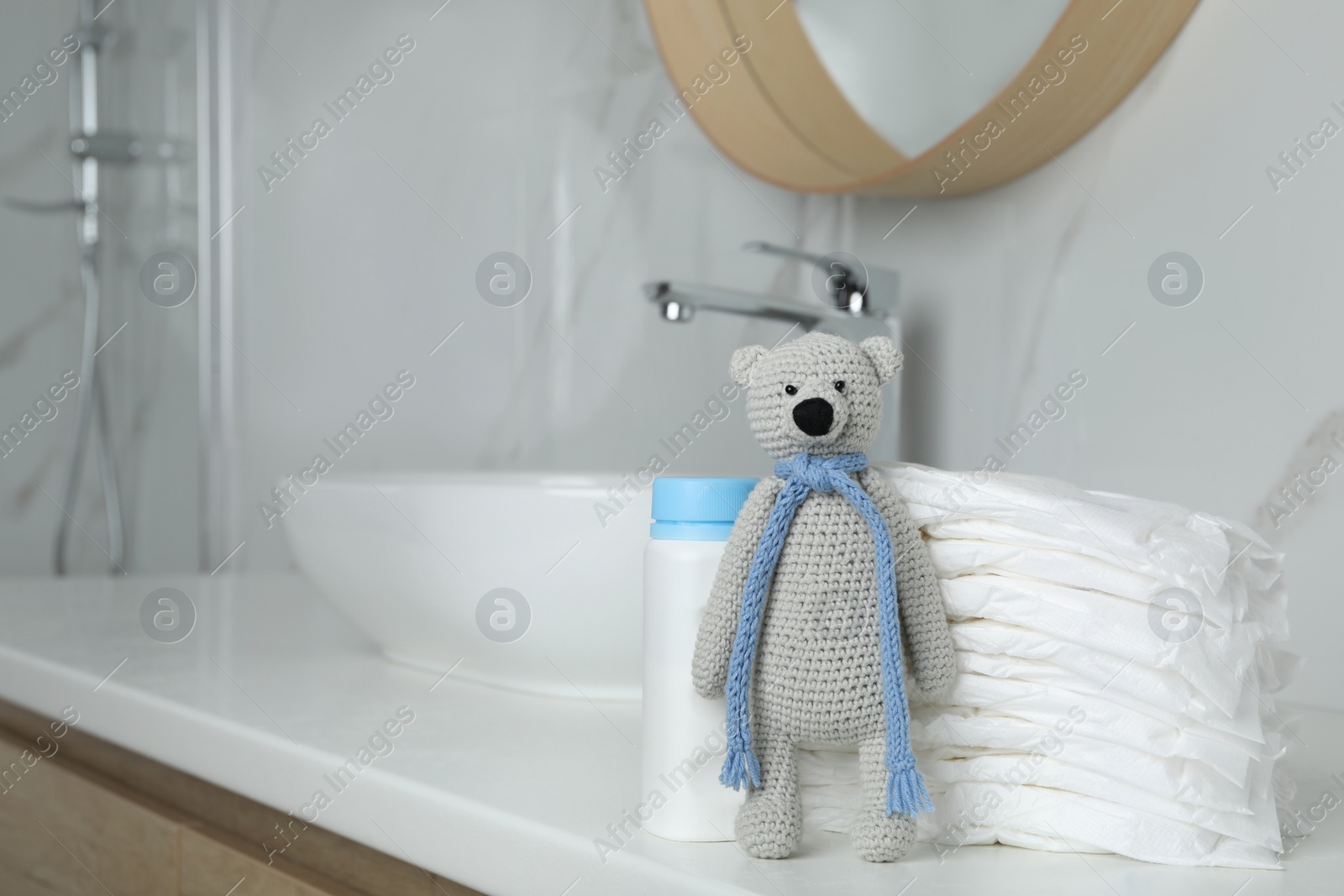 Photo of Stack of diapers and toy bear on counter in bathroom. Space for text