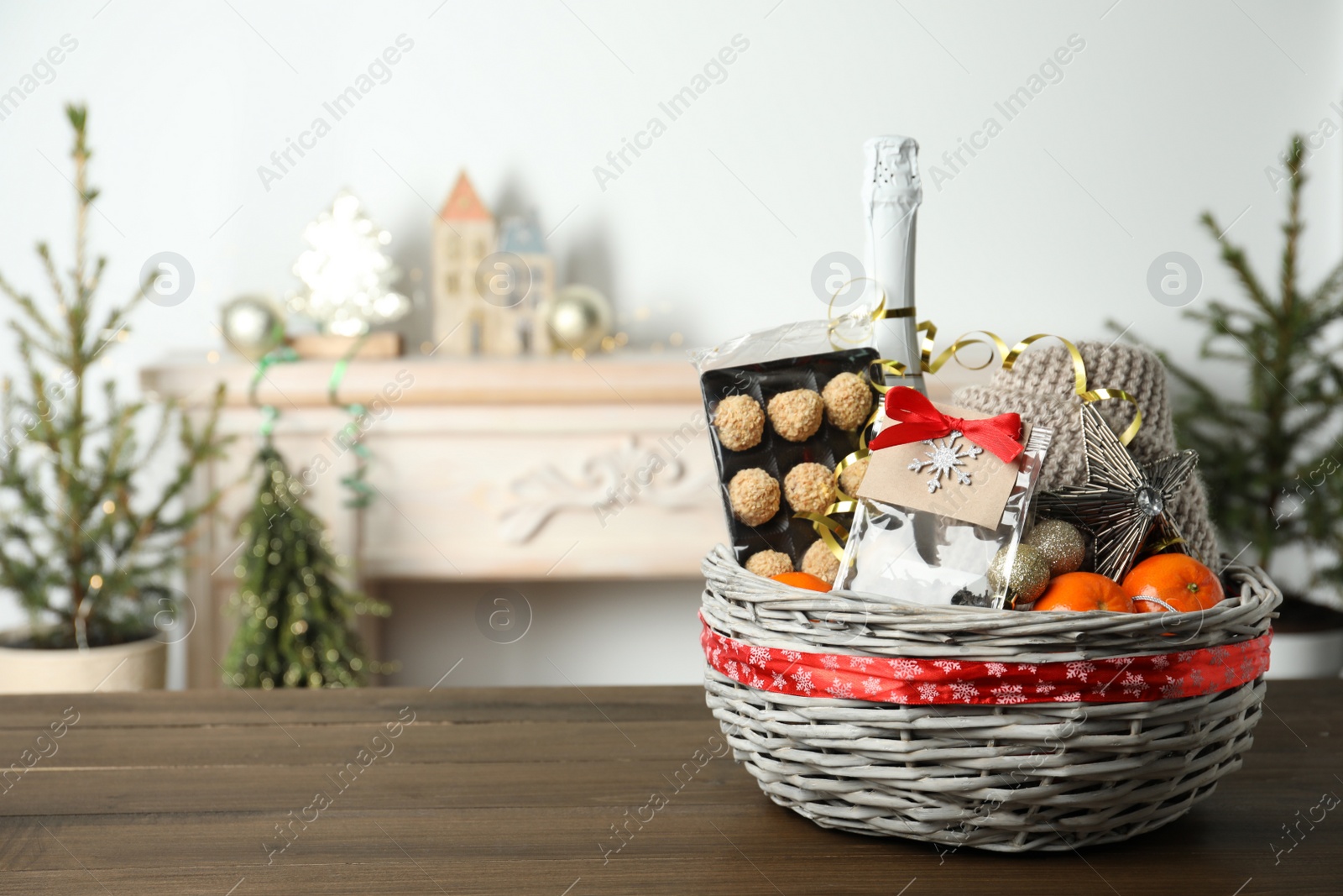 Photo of Wicker basket with Christmas gift set on wooden table. Space for text