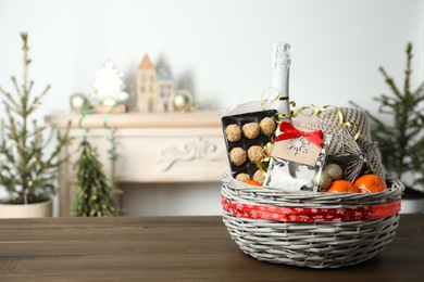 Wicker basket with Christmas gift set on wooden table. Space for text