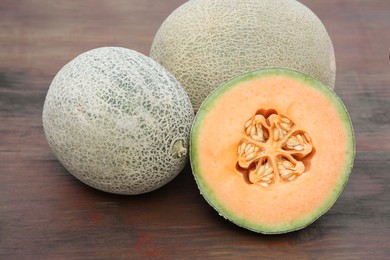 Photo of Whole and cut fresh ripe melons on wooden table