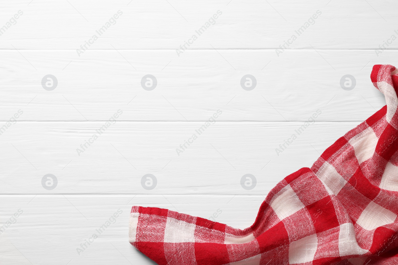 Photo of Red checkered tablecloth on wooden table, top view. Space for text