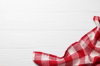 Photo of Red checkered tablecloth on wooden table, top view. Space for text