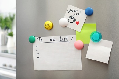 Photo of To do list, sheets of paper, note and magnets on refrigerator door in kitchen. Space for text