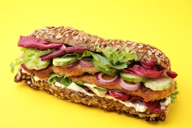 Photo of Delicious sandwich with schnitzel on yellow background, closeup