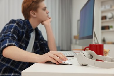 Photo of Teenage boy using computer in room, focus on hand. Internet addiction