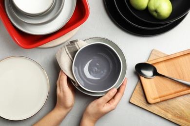Photo of Woman with clean dishware at grey table, top view