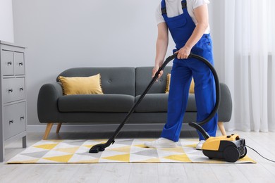 Photo of Dry cleaner's employee hoovering carpet with vacuum cleaner in room, closeup