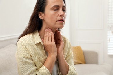 Mature woman doing thyroid self examination at home