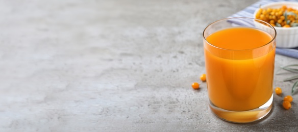 Delicious sea buckthorn juice on grey table, space for text. Banner design
