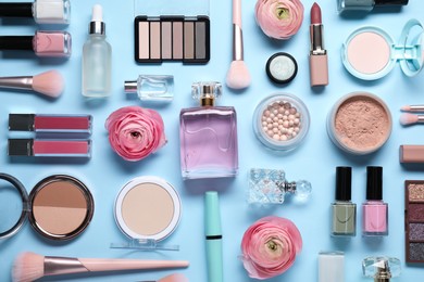 Flat lay composition with different makeup products and beautiful spring flowers on light blue background