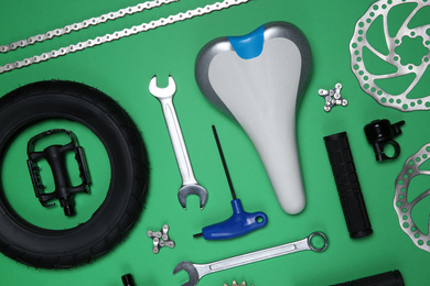 Photo of Set of different bicycle tools and parts on green background, flat lay