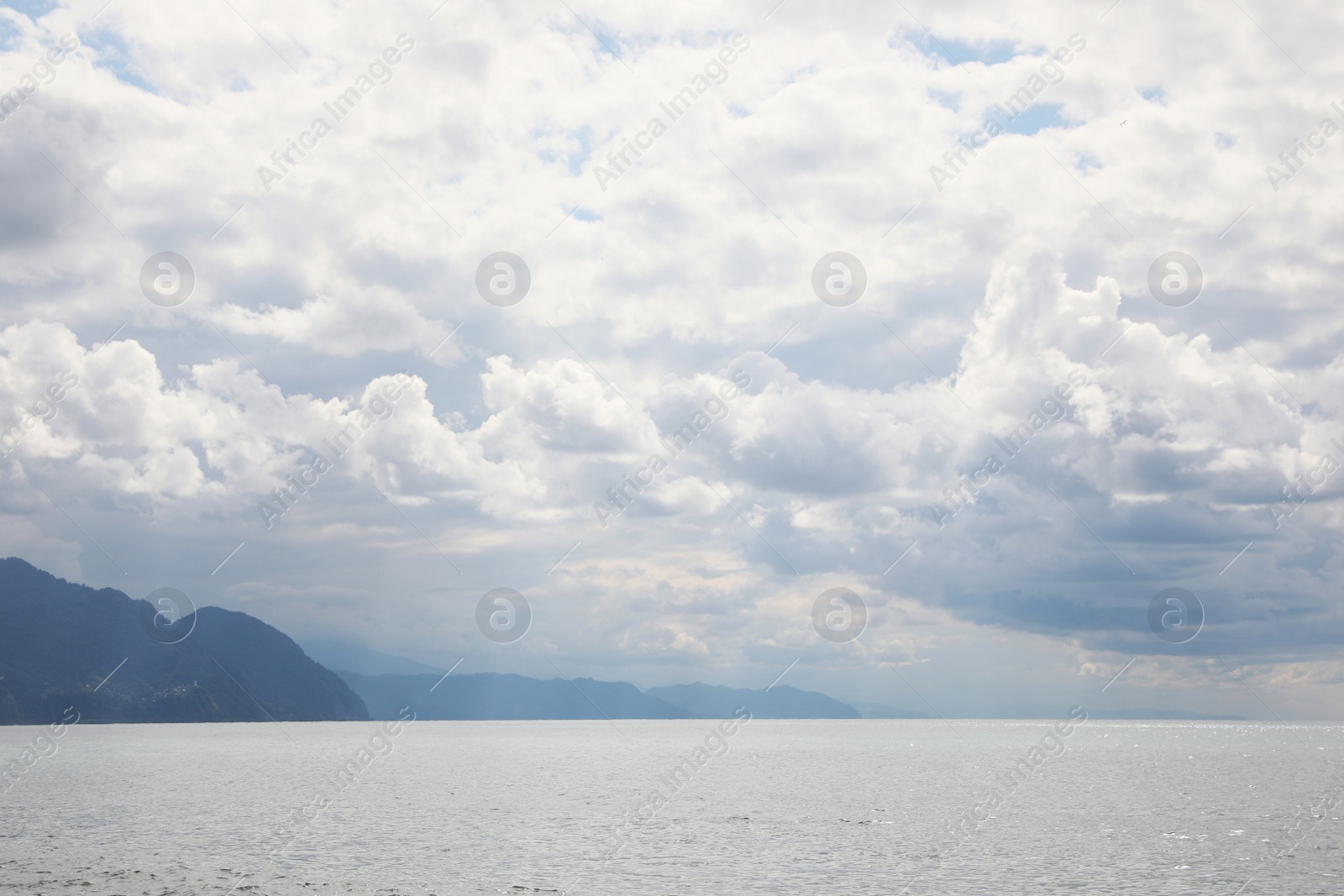 Photo of Picturesque view of beautiful sea and mountains under sky with fluffy clouds