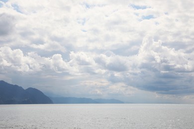 Photo of Picturesque view of beautiful sea and mountains under sky with fluffy clouds