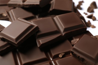 Photo of Pieces of delicious dark chocolate bar on white background, closeup