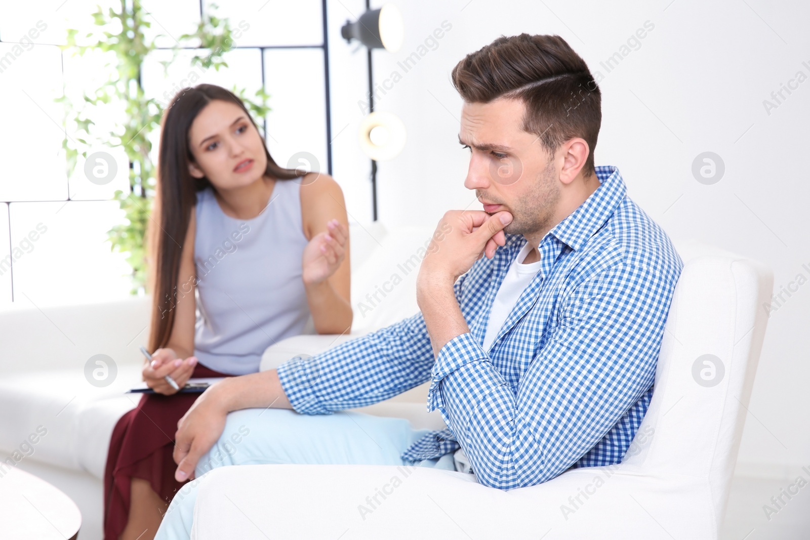 Photo of Depressed young man having appointment with psychologist in office