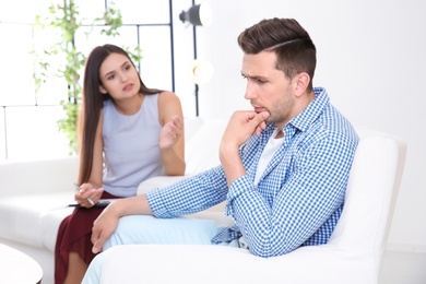 Depressed young man having appointment with psychologist in office