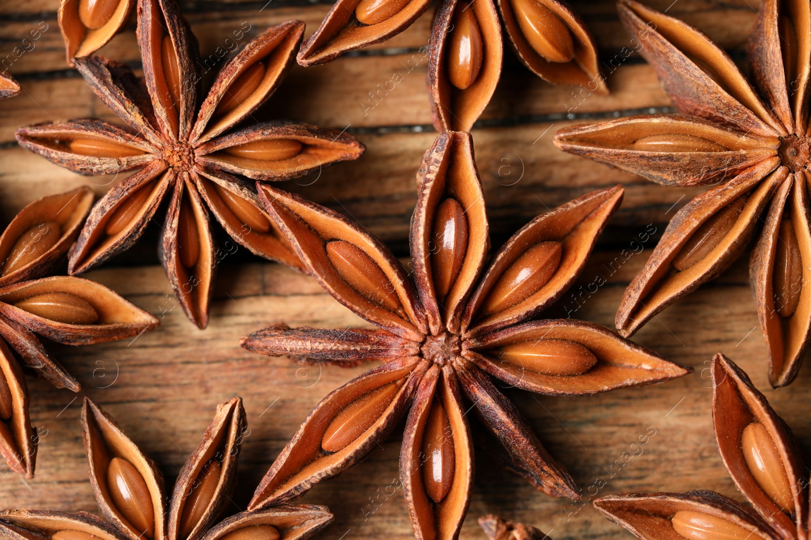 Photo of Aromatic anise stars on wooden table, flat lay