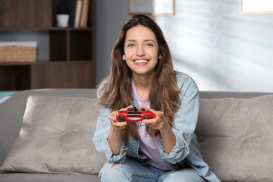 Photo of Happy woman playing video game with controller at home