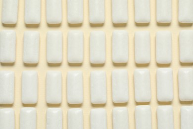 Photo of Tasty white chewing gums on beige background, flat lay