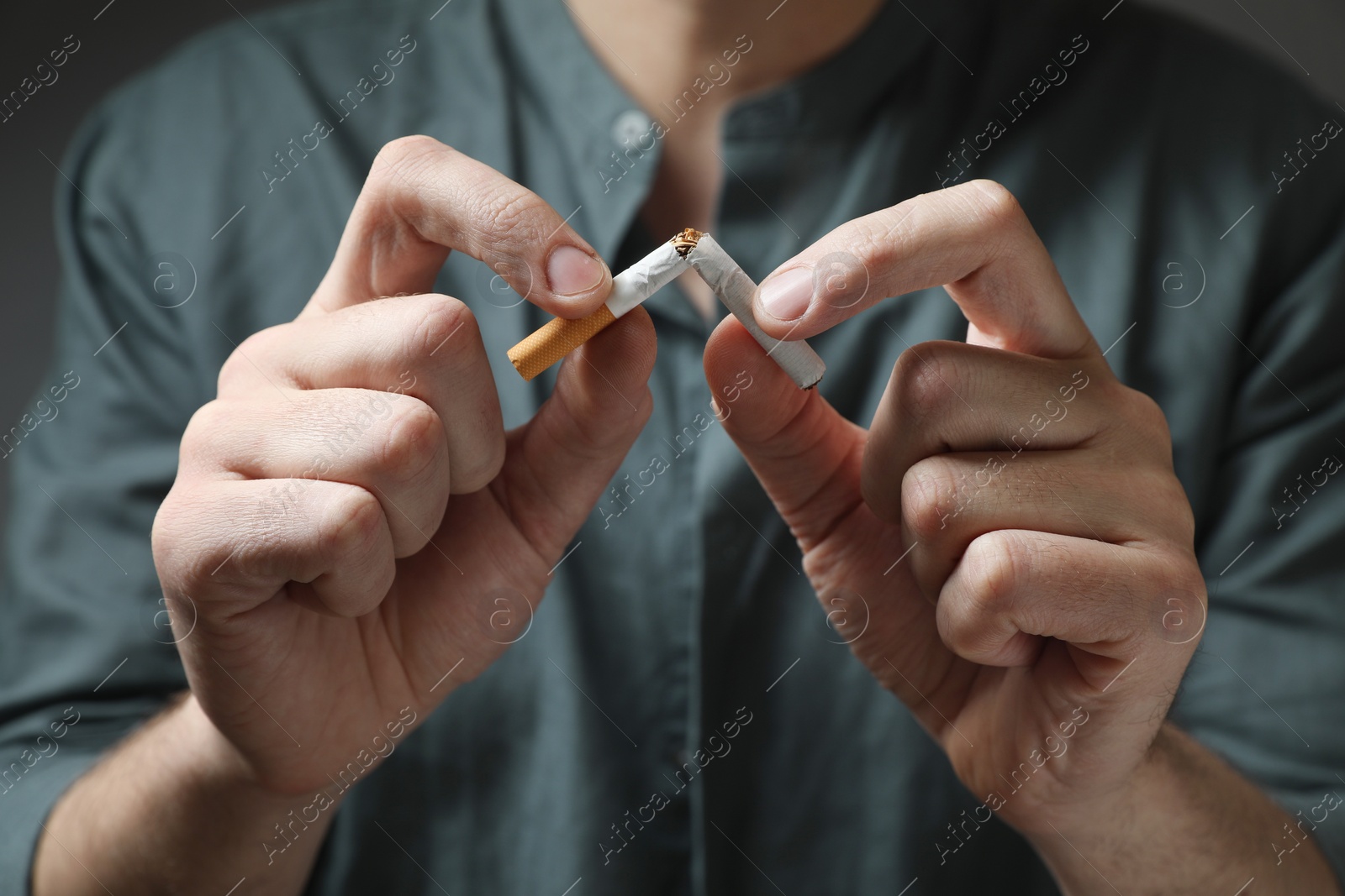 Photo of Stop smoking. Man holding broken cigarette, closeup