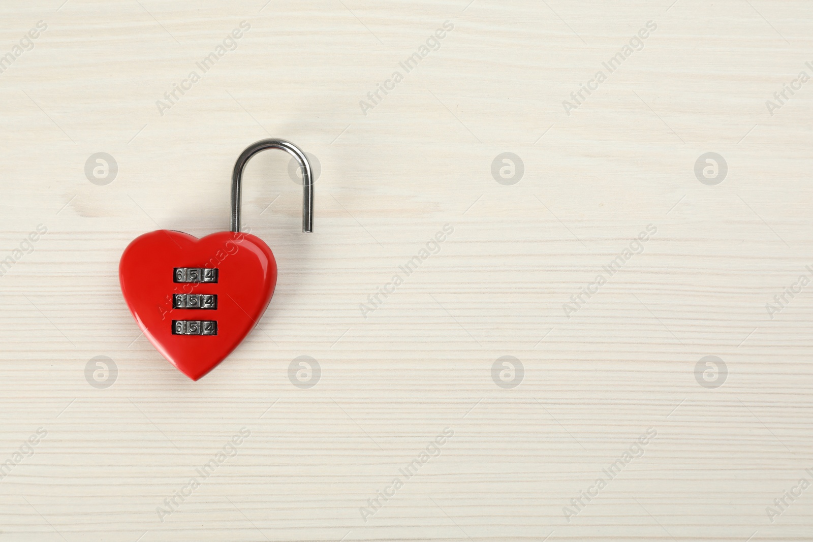 Photo of Red heart shaped combination lock on white wooden table, top view. Space for text