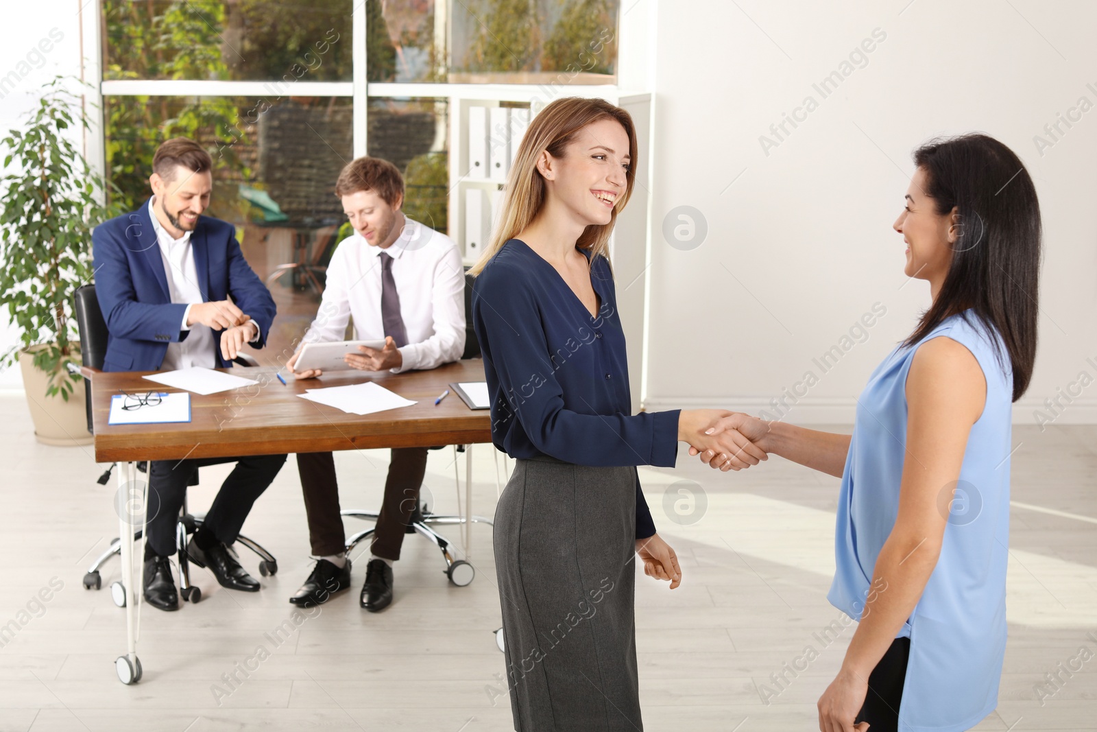 Photo of Human resources manager shaking hands with applicant during job interview in office