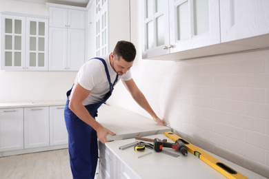Photo of Worker installing new countertop in modern kitchen