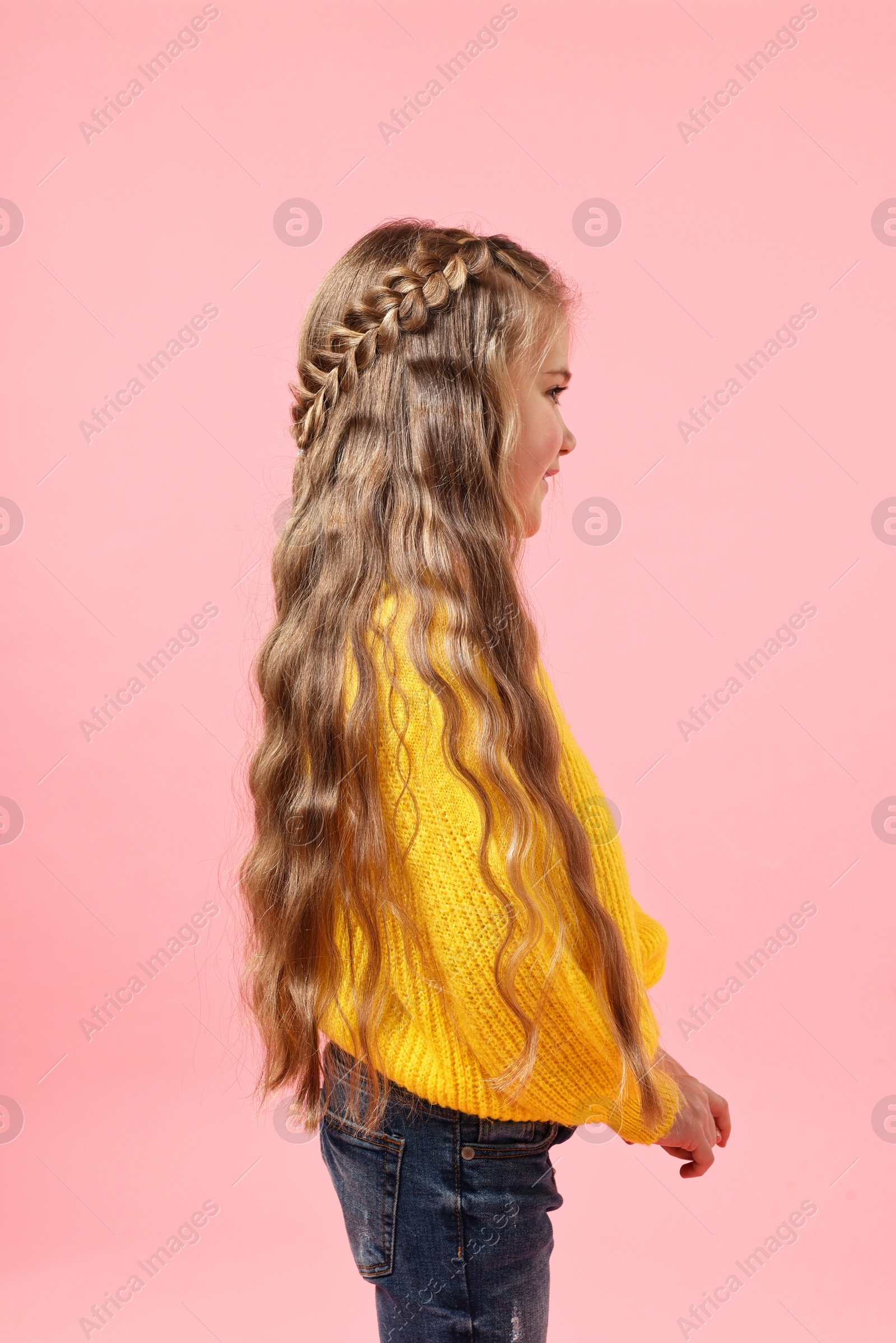 Photo of Cute little girl with braided hair on pink background