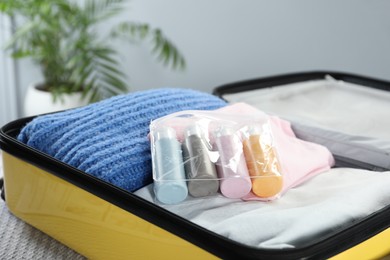 Photo of Plastic bag of cosmetic travel kit in suitcase indoors