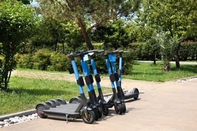 Photo of Many modern electric scooters in park. Rental service