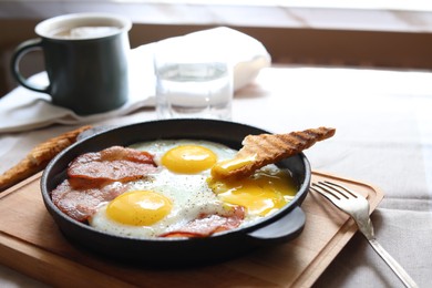 Photo of Tasty fried eggs with bacon and toast on table