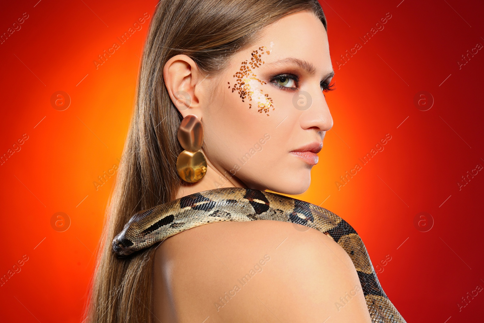 Photo of Beautiful woman with boa constrictor on bright colorful background, closeup