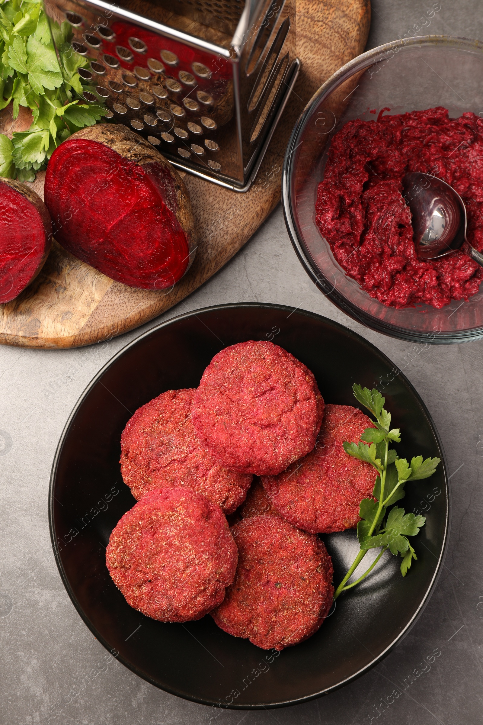 Photo of Delicious beetroot vegan cutlets and ingredients on light gray table, flat lay