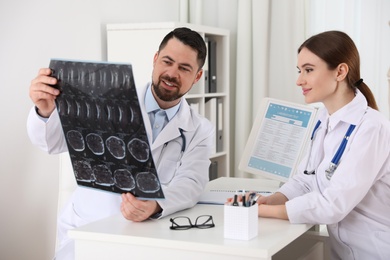 Photo of Orthopedists examining X-ray picture at desk in clinic