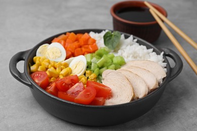 Delicious poke bowl with meat, egg, rice and vegetables on grey table, closeup