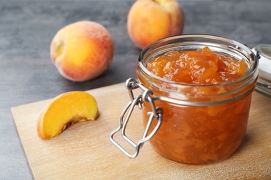 Jar with tasty peach jam on table