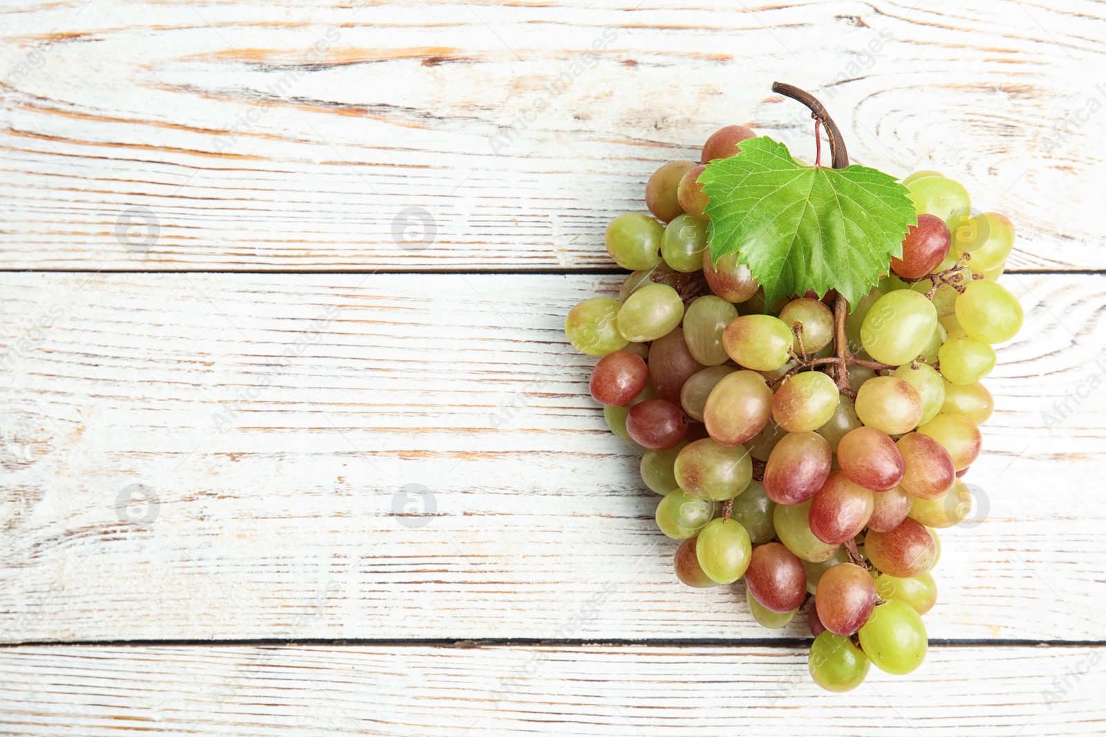 Photo of Fresh ripe juicy grapes and space for text on wooden background, top view