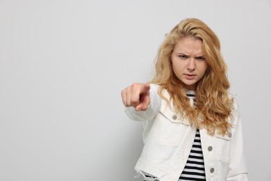 Photo of Aggressive young woman pointing on white background. Space for text