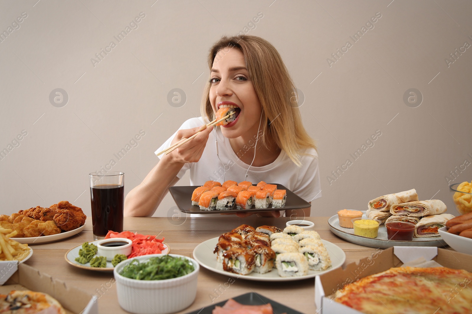 Photo of Food blogger eating at table against beige background. Mukbang vlog