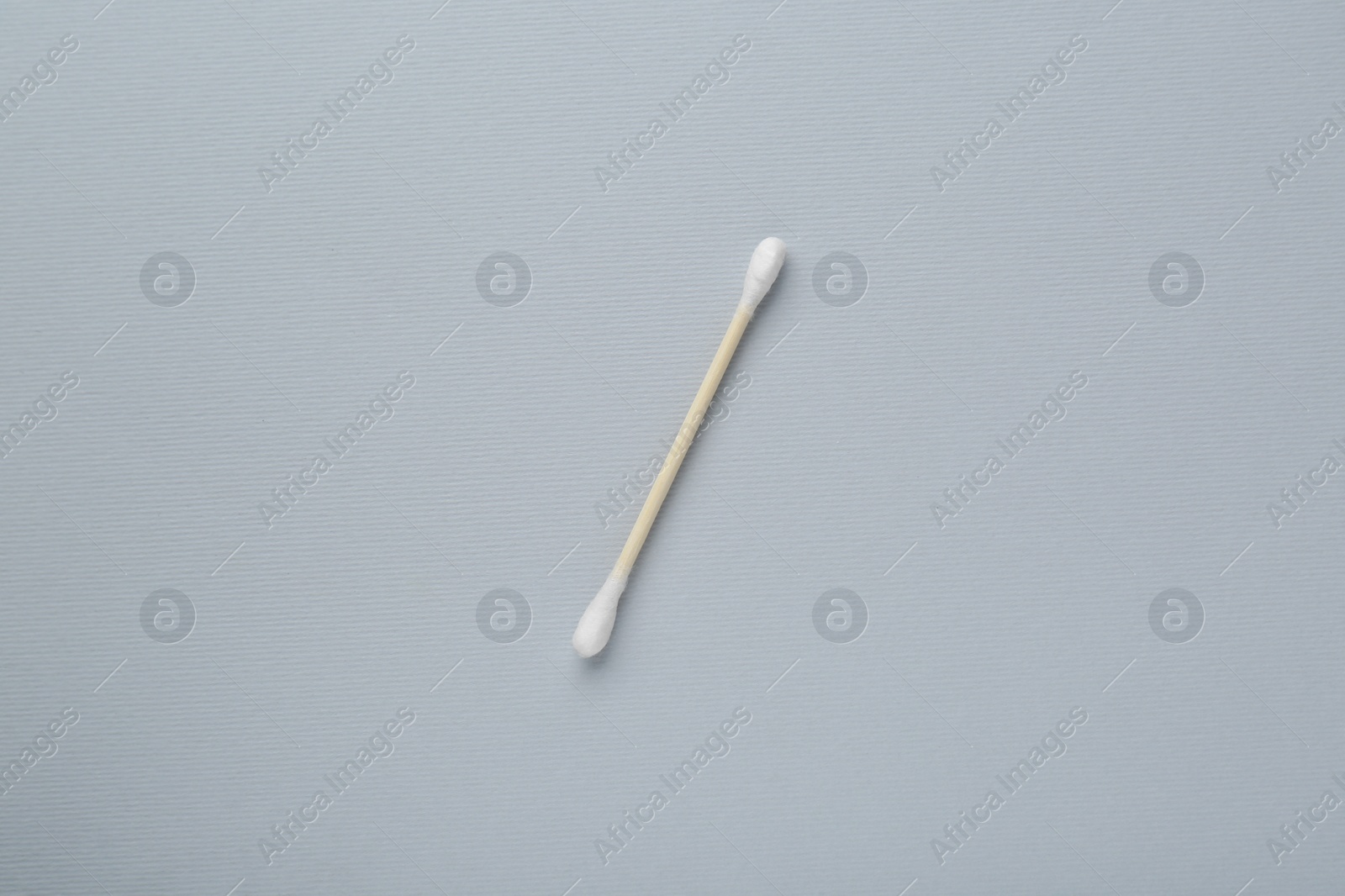 Photo of One wooden cotton bud on light grey background, top view