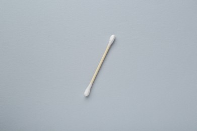 One wooden cotton bud on light grey background, top view