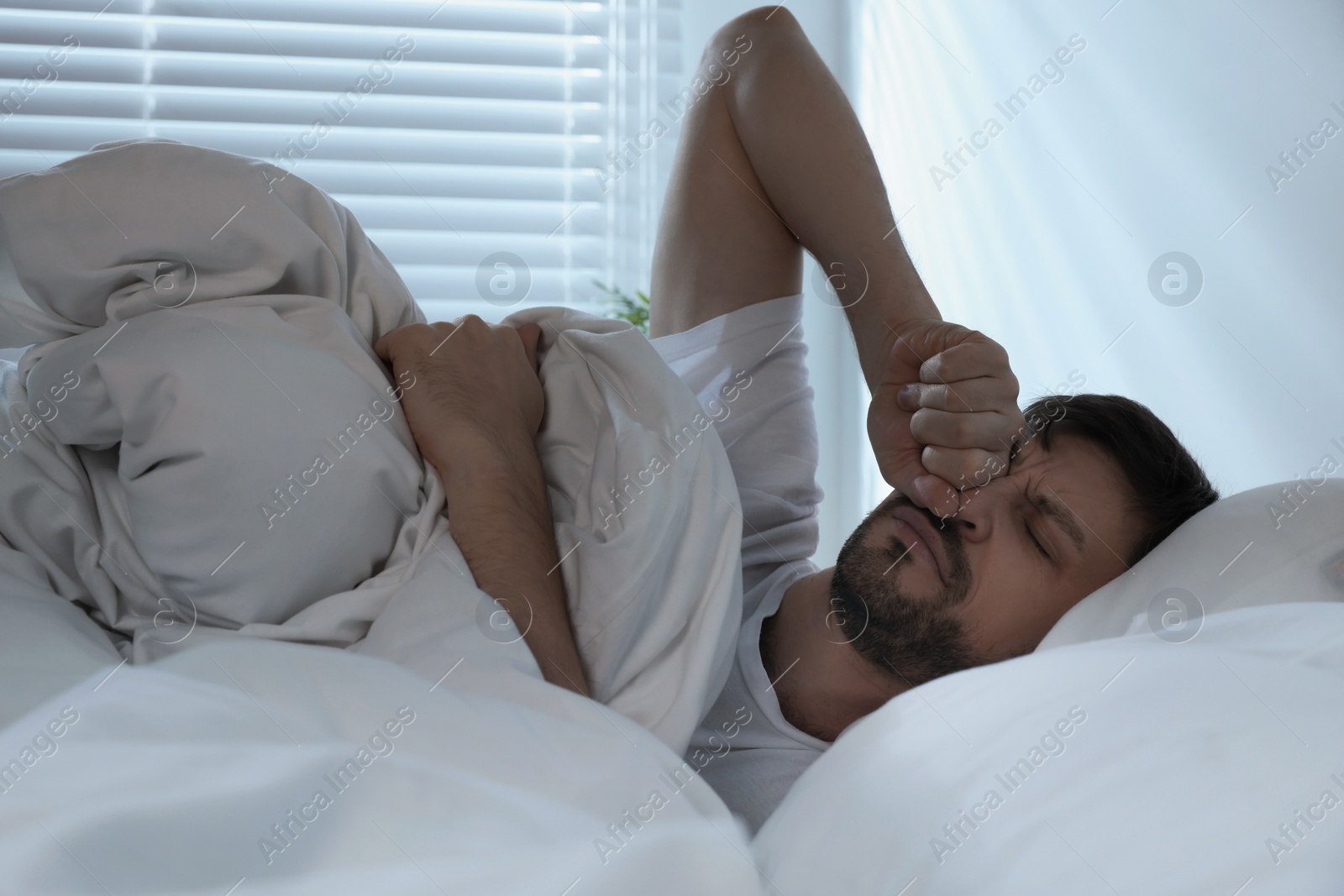 Photo of Sleepy man awaking in bed at home