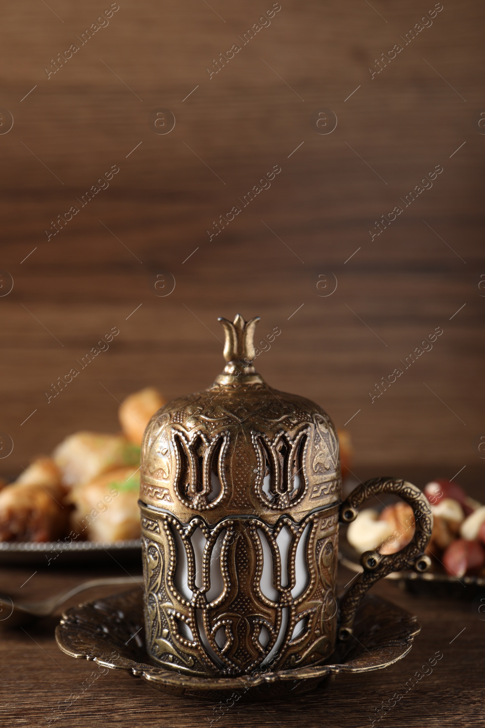 Photo of Beautiful vintage cup holder, nuts and baklava dessert on wooden table, space for text