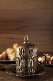 Photo of Beautiful vintage cup holder, nuts and baklava dessert on wooden table, space for text