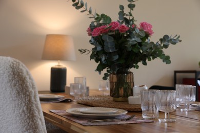 Beautiful table setting with bouquet indoors. Roses and eucalyptus branches in vase