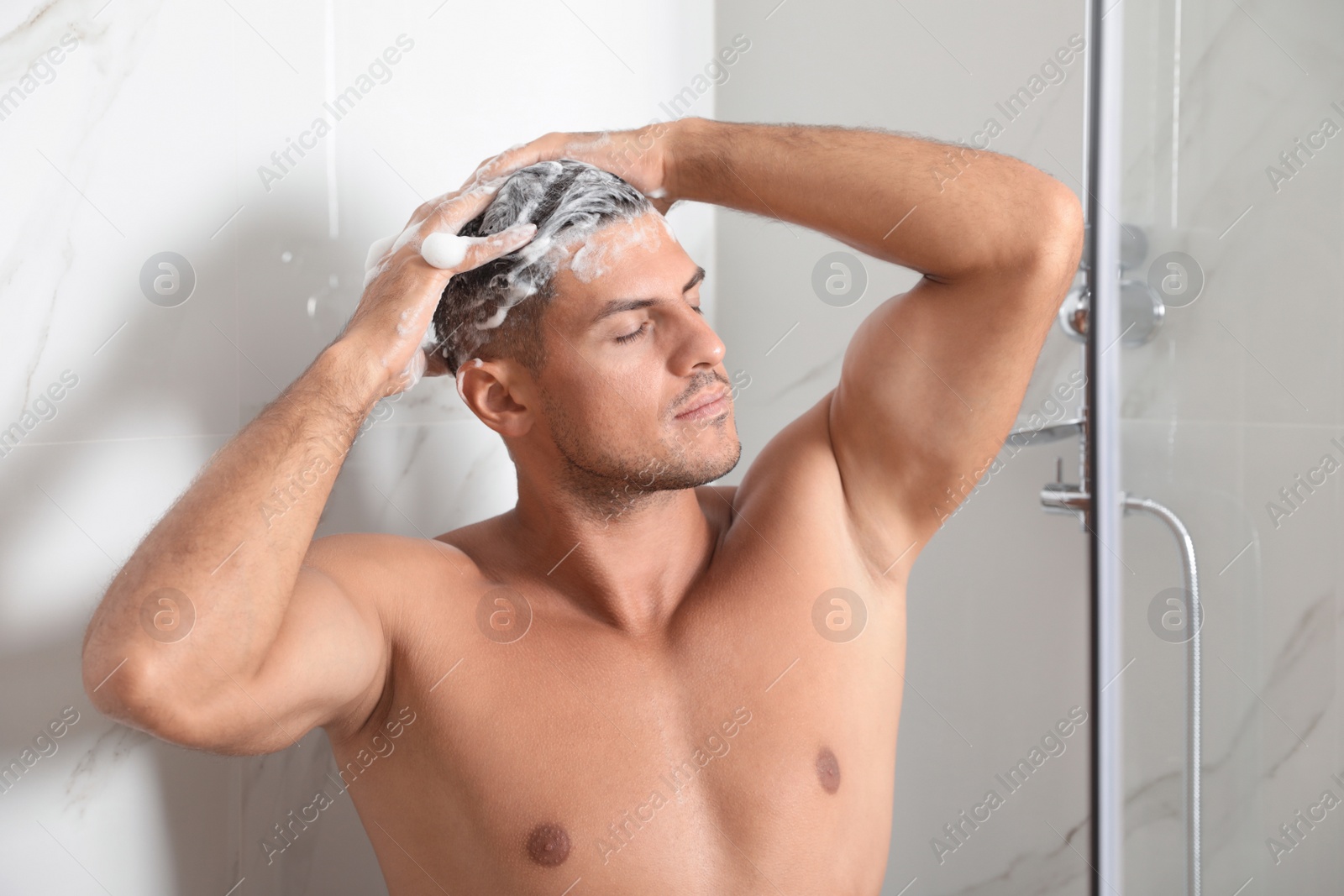 Photo of Handsome man washing hair in shower at home