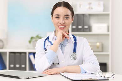 Medical consultant with stethoscope at table in clinic