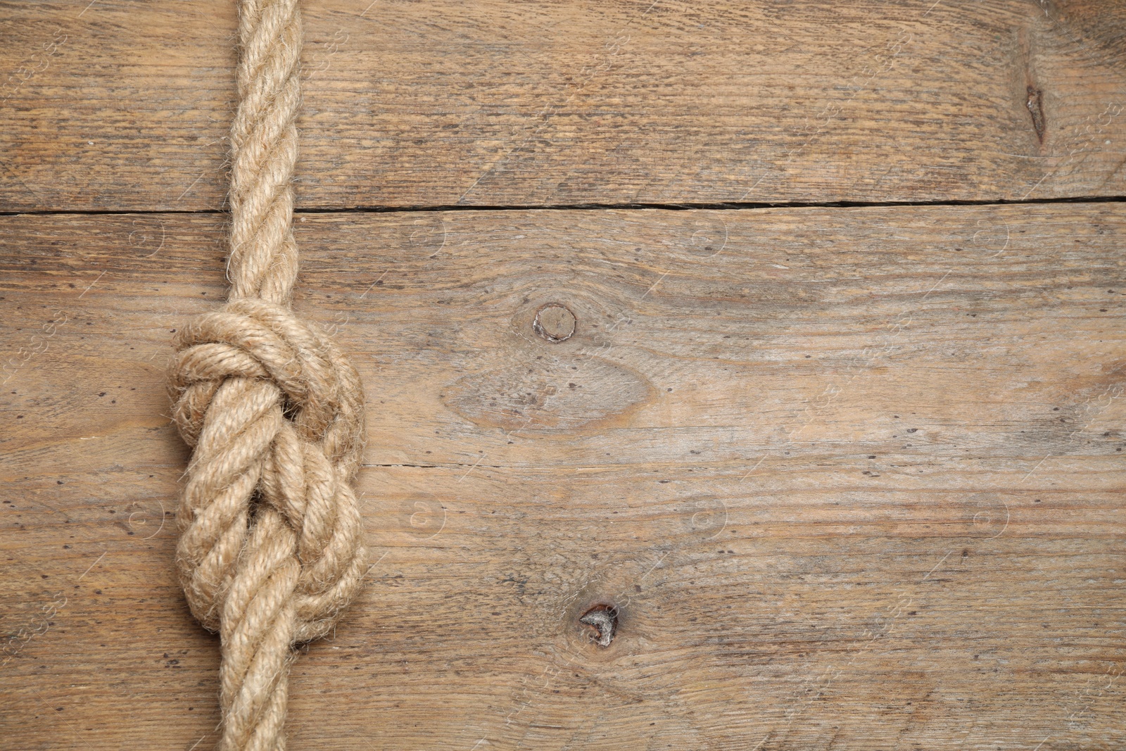 Photo of Top view of linen rope with knot on wooden background, space for text. Unity concept