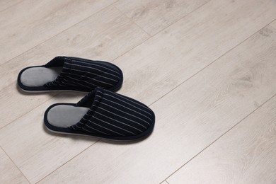 Photo of Pair of stylish slippers on white wooden floor, space for text
