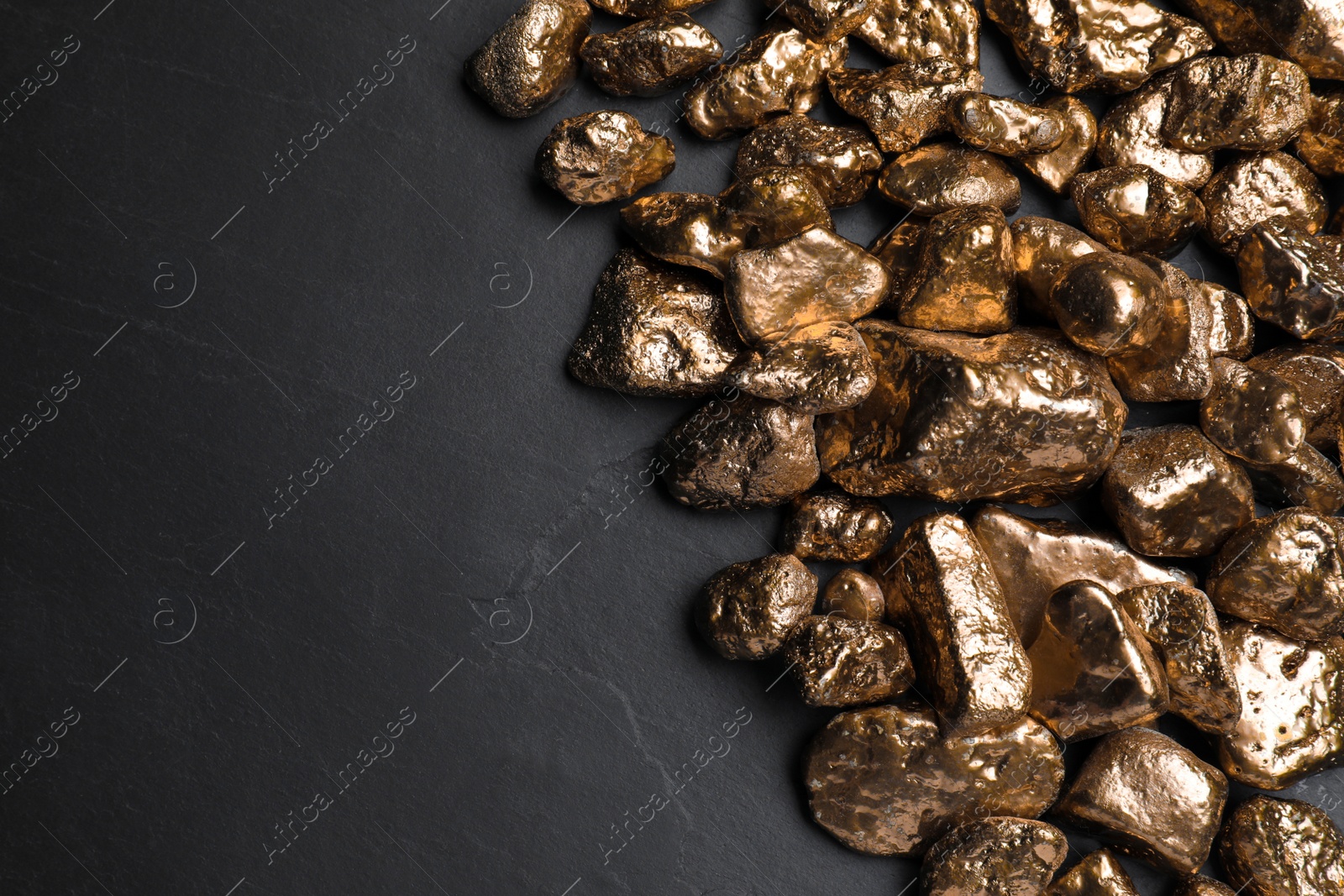 Photo of Pile of gold nuggets on black table, flat lay. Space for text